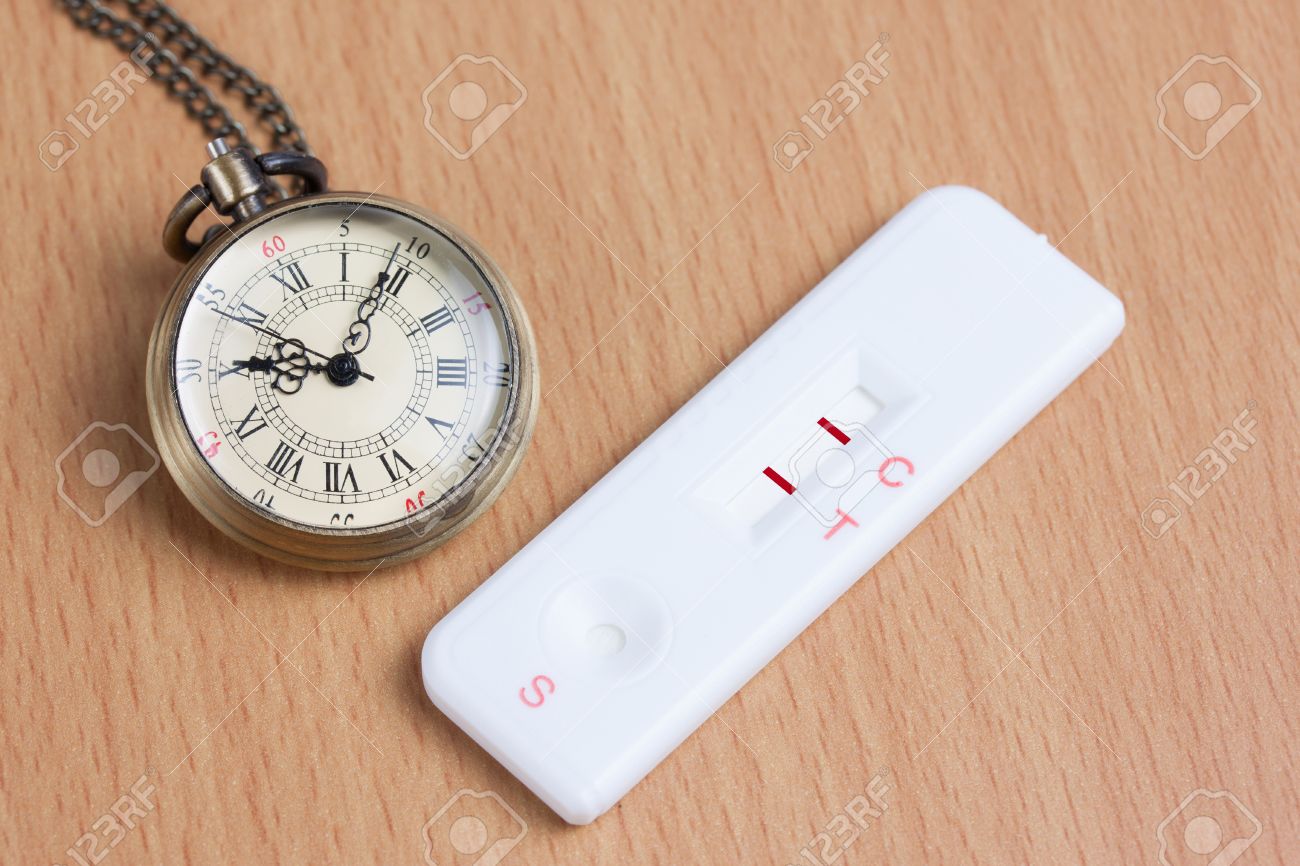 Pocket watch with pregnancy test on wooden table, Time to born ,